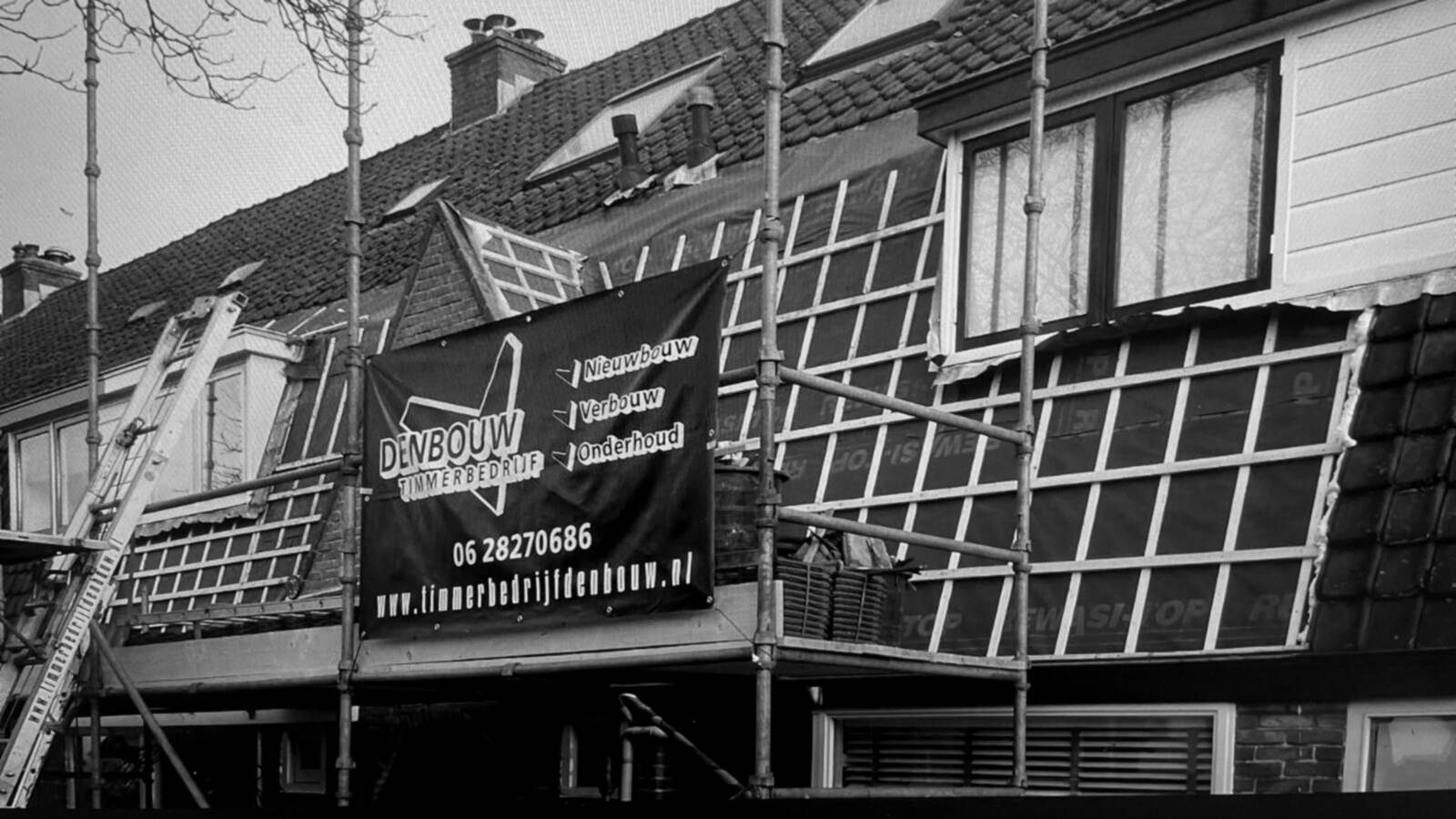 Werkbord van Timmerbedrijf Den Bouw op een steiger bij een verbouwing