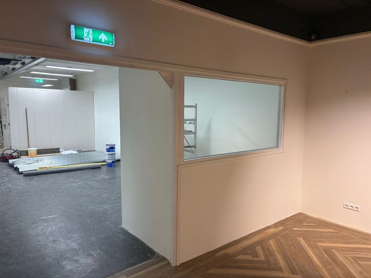 Afgewerkt interieur met glazen scheidingswand en houten vloer